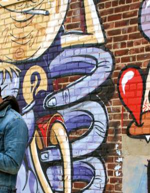 One of Brooklyn's many resident hipsters takes a break alongside some local street art.