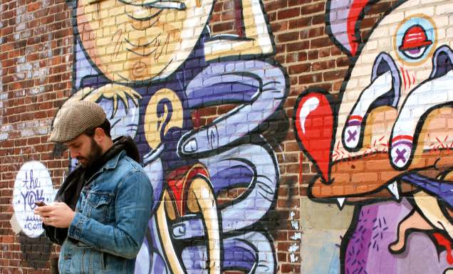 One of Brooklyn's many resident hipsters takes a break alongside some local street art.