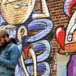 One of Brooklyn's many resident hipsters takes a break alongside some local street art.
