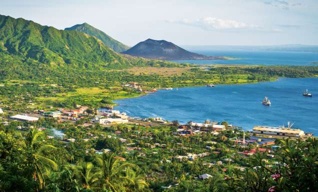 Rabaul with the dark cone of Mt Tavurvur on the horizon.