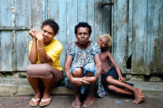 A Tolai woman and her grandchildren outside their Maira home.