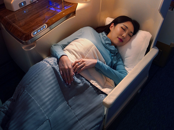 a woman sleeping in the new business class loungewear onboard Emirates A380