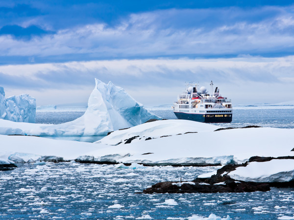 Large cruise ship sailing through the icy waters of Antarctica