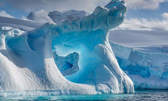 A dramatically shaped and weather eroded iceberg floating in Wilhemina Bay Antarctica