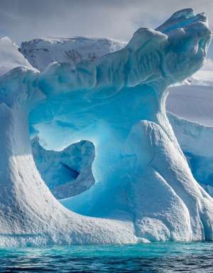 A dramatically shaped and weather eroded iceberg floating in Wilhemina Bay Antarctica