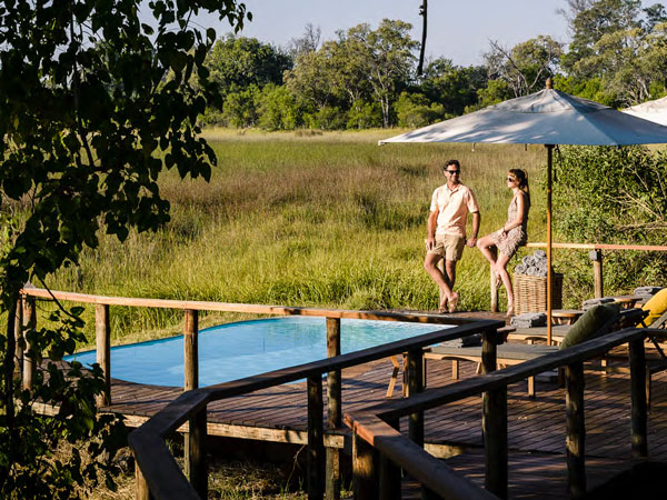 a couple standing by the pool at Get closer to nature at Sanctuary Stanley’s Camp.