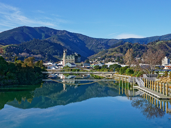 anorama of Nelson City, reflected in the still waters of the Maitai River, New Zealand.