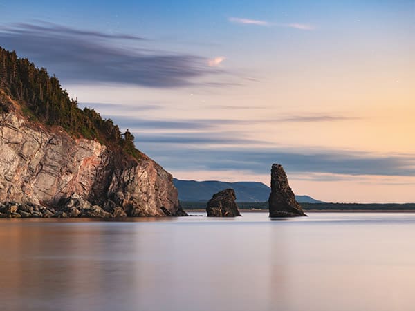 A long exposure of the calm ocean around a rock formation on Cape Breton Island, Nova Scotia