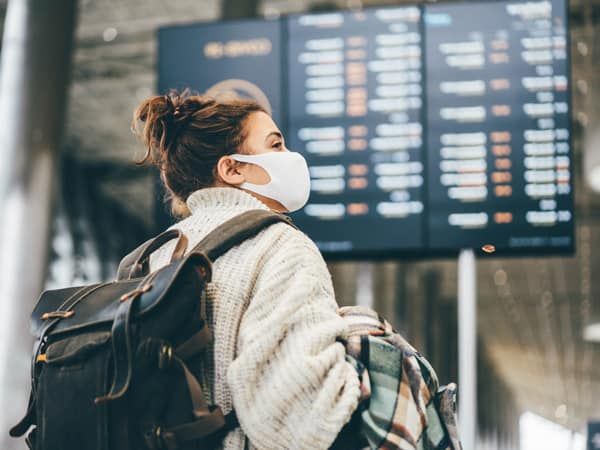 Woman in protection mask looking at information in airport.