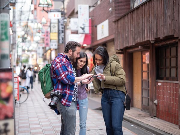 Tourists are walking on the street of Tokyo, Japan and use Google Translate to communicate.