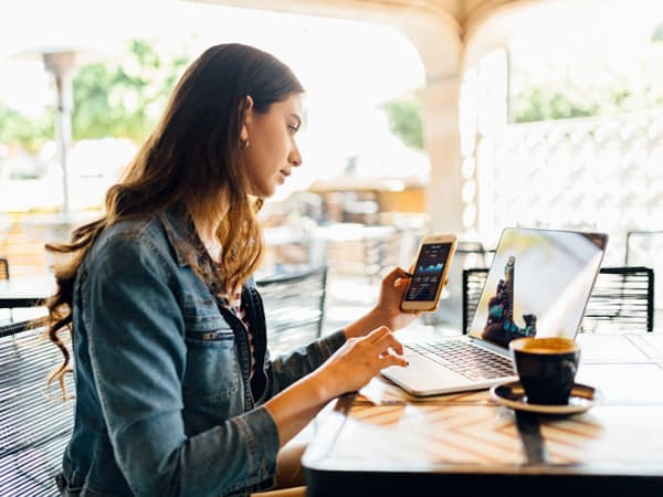 A woman uses Hotspot Shield in a public cafe to protect her phone and laptop.