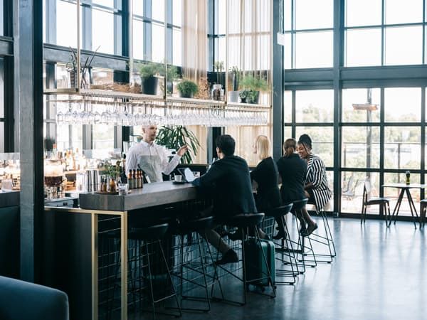 A group of people sit at the bar in the airport lounge.