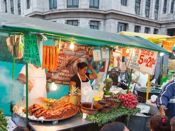 People eating and socialising at a vibrant food market stall in Mexico City. (Image: Getty Images)