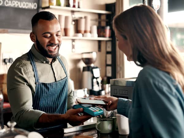 Shot of a young man accepting a digital payment from a customer in a cafe.