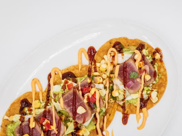 Tuna Tostadas with corn salad, guacamole and chipotle on a white background. (Image: Getty Images)