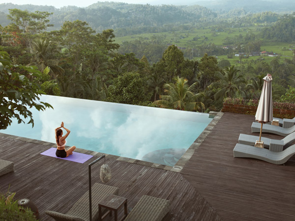 Girl Doing Yoga On Poolside In Morning In Bali, Indonesia. Young Slim Woman In Sportswear Sitting In Lotus Pose Or Padmasana On Sport Mat Near Infinity Pool Against Tropical Landscape.