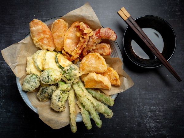 Horizontal flat lay of Japanese vegetable tempura recipe with ginger ponzu sauce , black background with copy space