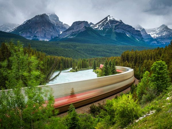 Train passing through the Morant's Curve in bow valley with Rocky Mountains in the background, Banff National Park, Alberta Canada.