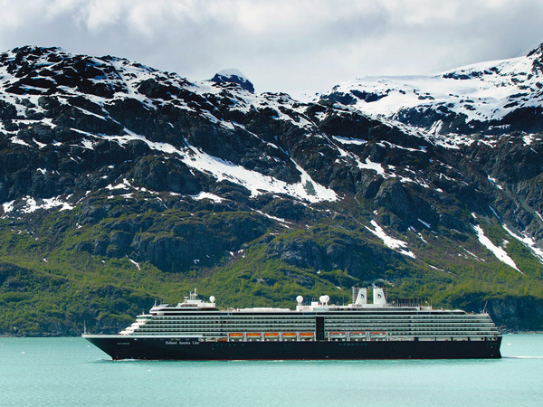 A Holland America Cruise ship sailing through snow-capped mountains
