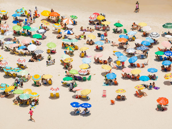 Aerial view of colourful beachgoers on a wide sand beach