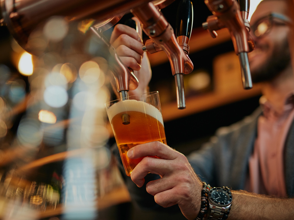 A barman pouring beer while standing in pub