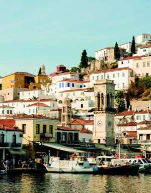Wide shot of boats on Hydra Harbour with buildings around. Greece.