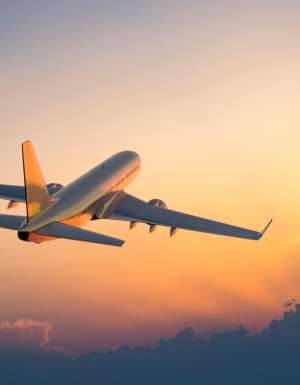 Passenger airplane flying above clouds during sunrise