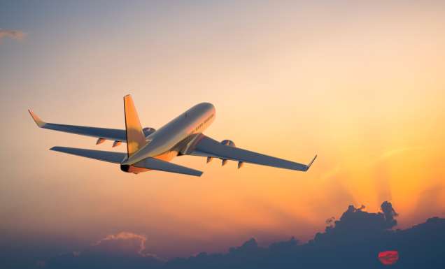 Passenger airplane flying above clouds during sunrise