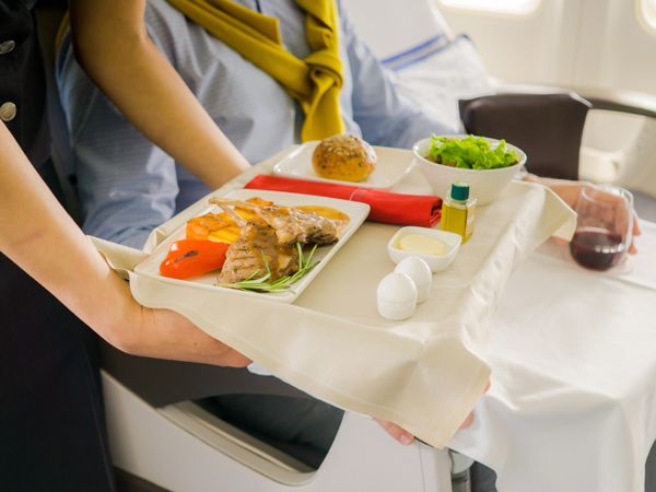 Flight attendant serving meal in an airplane