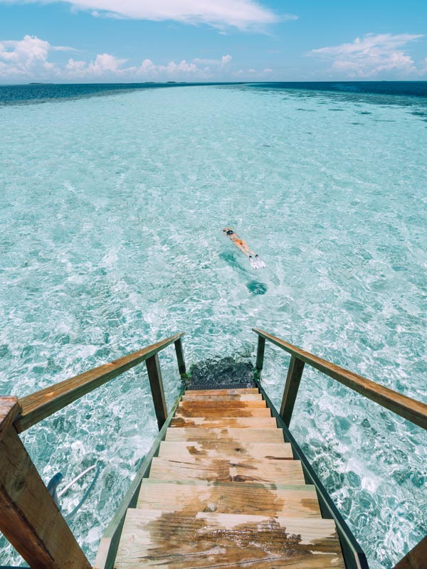 Young adult woman snorkeling in a turquoise clear sea in Maldives