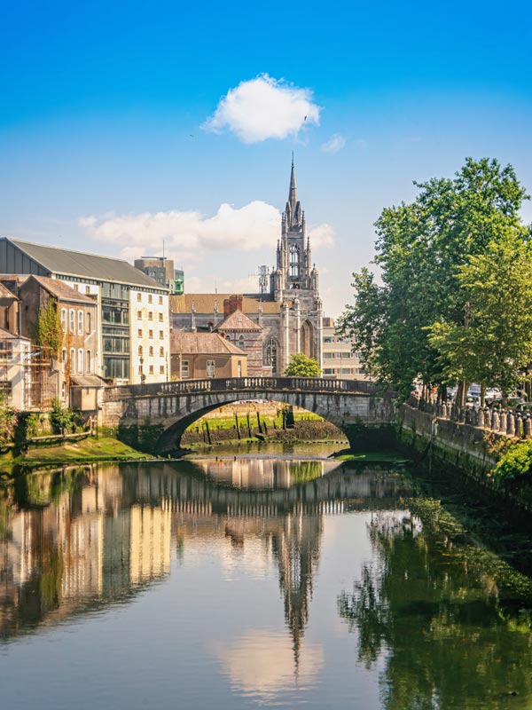 Parliament Bridge on river Lee and Holy Trinity Roman Catholic Church on a sunny summer day