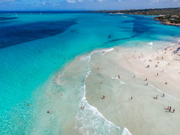 aerial of blue waters approaching the white-sand beach of Sardinia