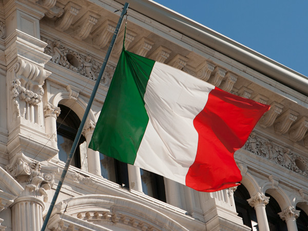 an Italian flag hanging over the facade of Trieste's City Hall
