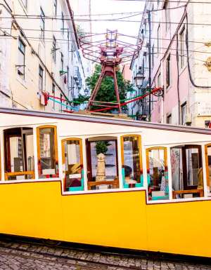 a yellow-coloured tram traversing along the Lisbon streetscape