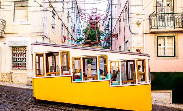 a yellow-coloured tram traversing along the Lisbon streetscape