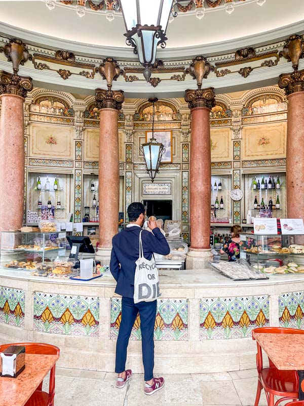 a man standing in front of a traditional bakery counter in Lisbon