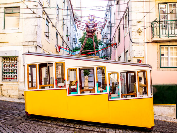 a yellow-coloured tram traversing along Lisbon streets