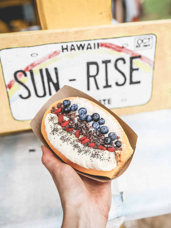 a hand holding a papaya bowl at Outrigger’s Sunrise Shack