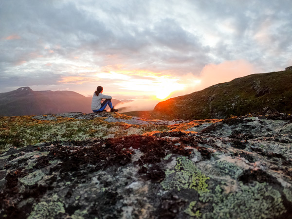 Woman sits watching sunset in trollheiman Mountain, Todalen, Norway