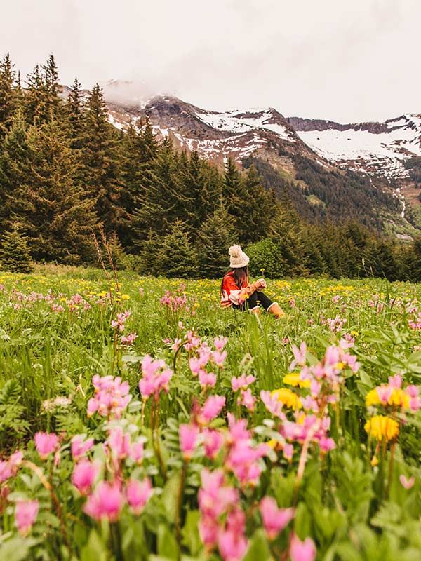 Sitting in a field of flowers near Chilkoot Lake while visiting Haines, Alaska
