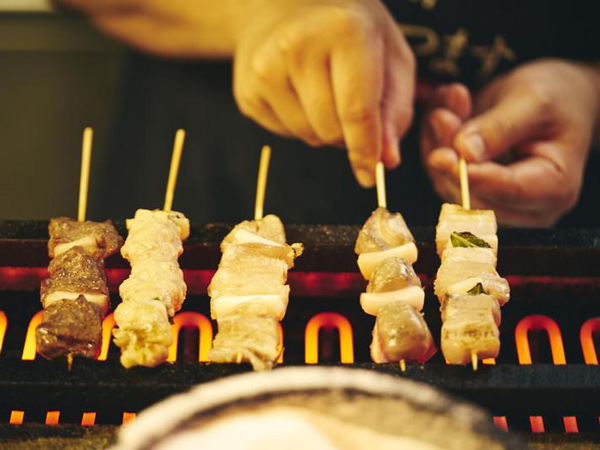 a person grilling meats in skewers