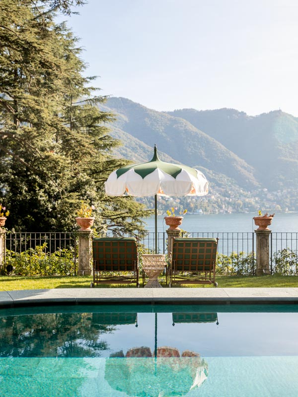 an outdoor pool with sun lounger and umbrella