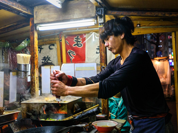 a man cooking a meal at a Yatai Food Stall in Fukuoka