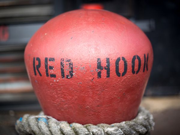 a Red Hook signage printed on an antique red bollard