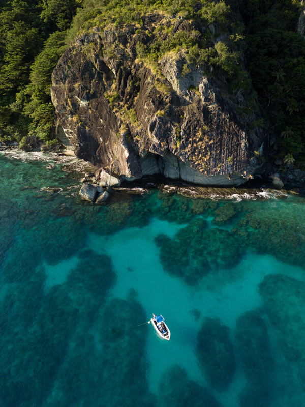 an aerial view of a boat passing through the waters of Likuliku MonuRiki Island