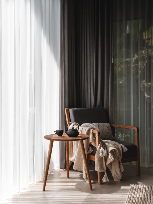 a chair beside a curtain inside Desa Hay sustainable hotel in Bali