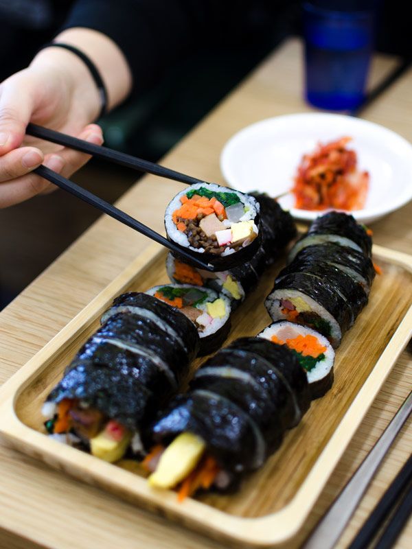 a hand reaching for Gimbap or seaweed rice rolls