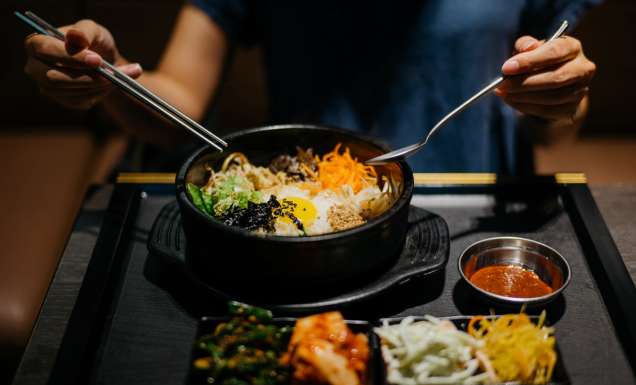 Woman eating bibimbap in Korean restaurant