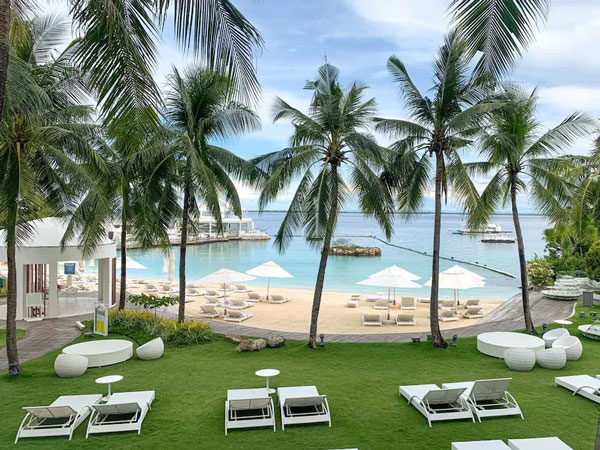 sun loungers on the palm-fringed beach at Movenpick Hotel, Cebu, Philippines