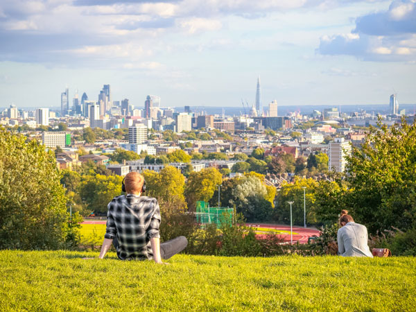 a man sitting on the grass while admiring the scenic view at Parliament Hill, London